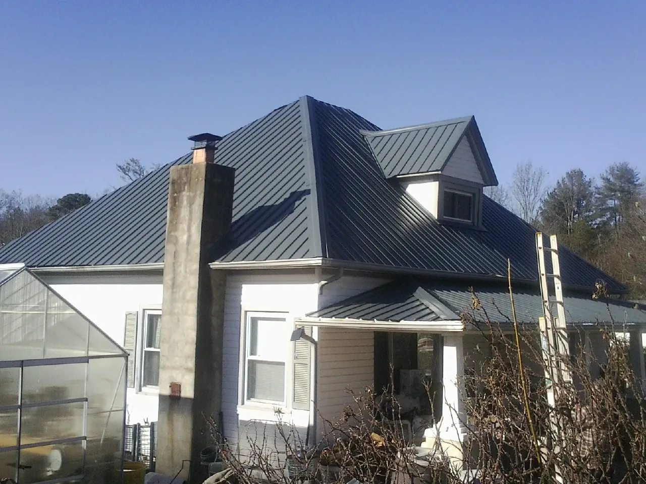 Dark blue standing seam metal roof on a white farmhouse with dormer — Slate & Tile Roof Repair by Roofing Brothers in Halbur