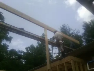 Carpenter setting a ridge beam over a new addition frame — Ice Dam Removal by Roofing Brothers in Halbur