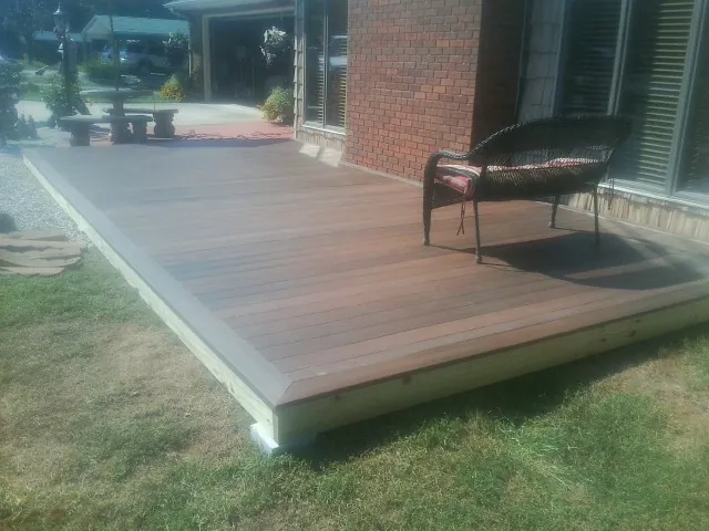New wood deck and wicker chair beside a brick house in Halbur