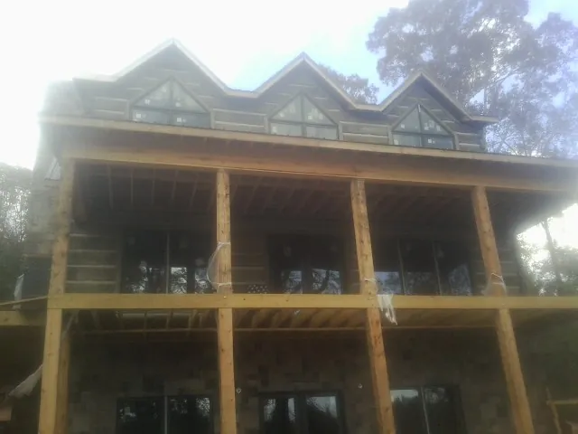 Dormers and porch framing on a large log home under construction — Roof Coating work by our crew in Halbur