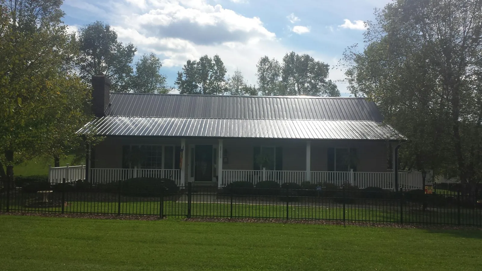 Gray metal roof on a brick ranch with a full width front porch — Gutter Guard Installation work by our crew in Halbur