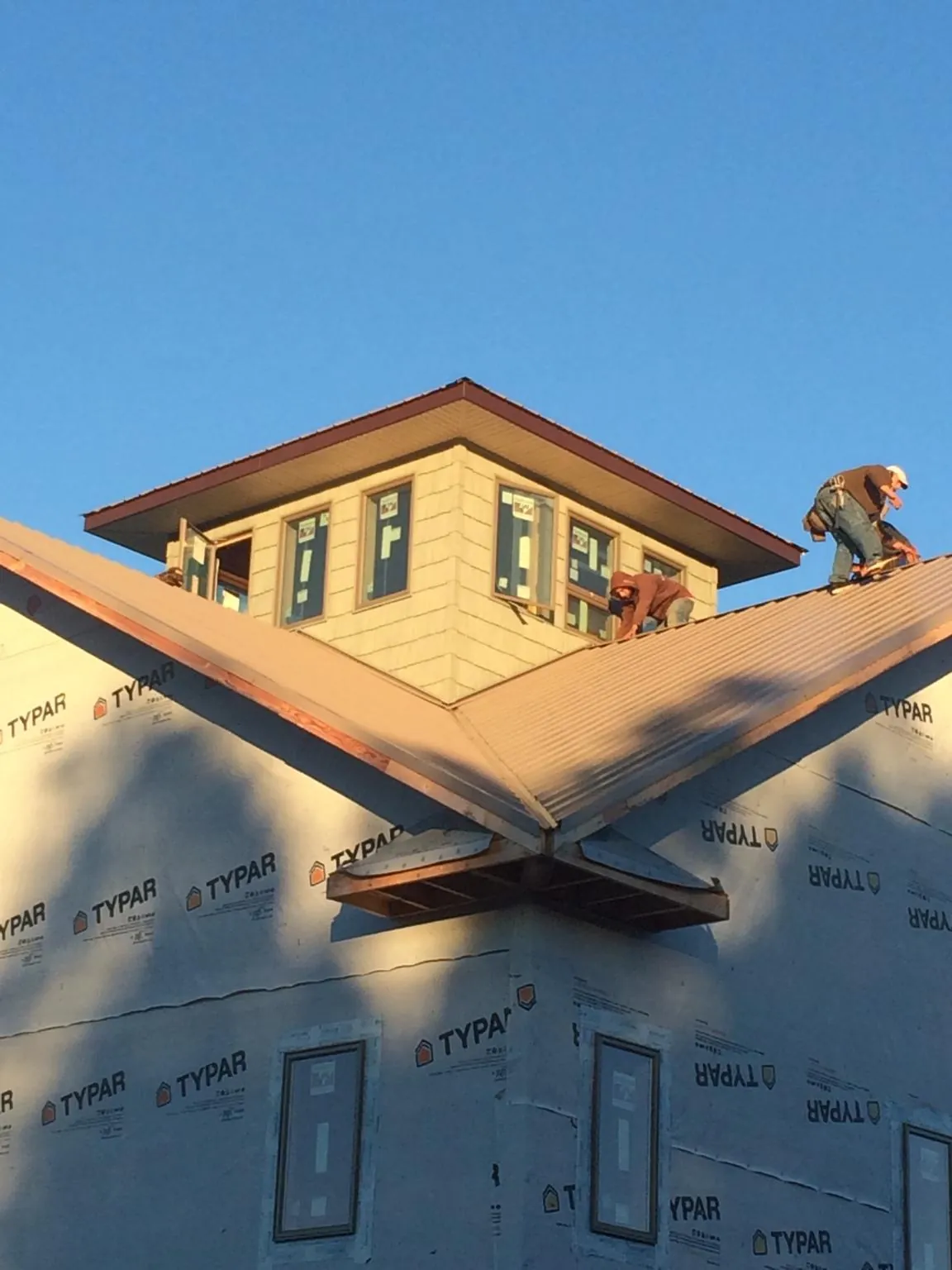Roofers working around a rooftop cupola on a new metal roof at sunset — Roof Waterproofing in Halbur by Roofing Brothers